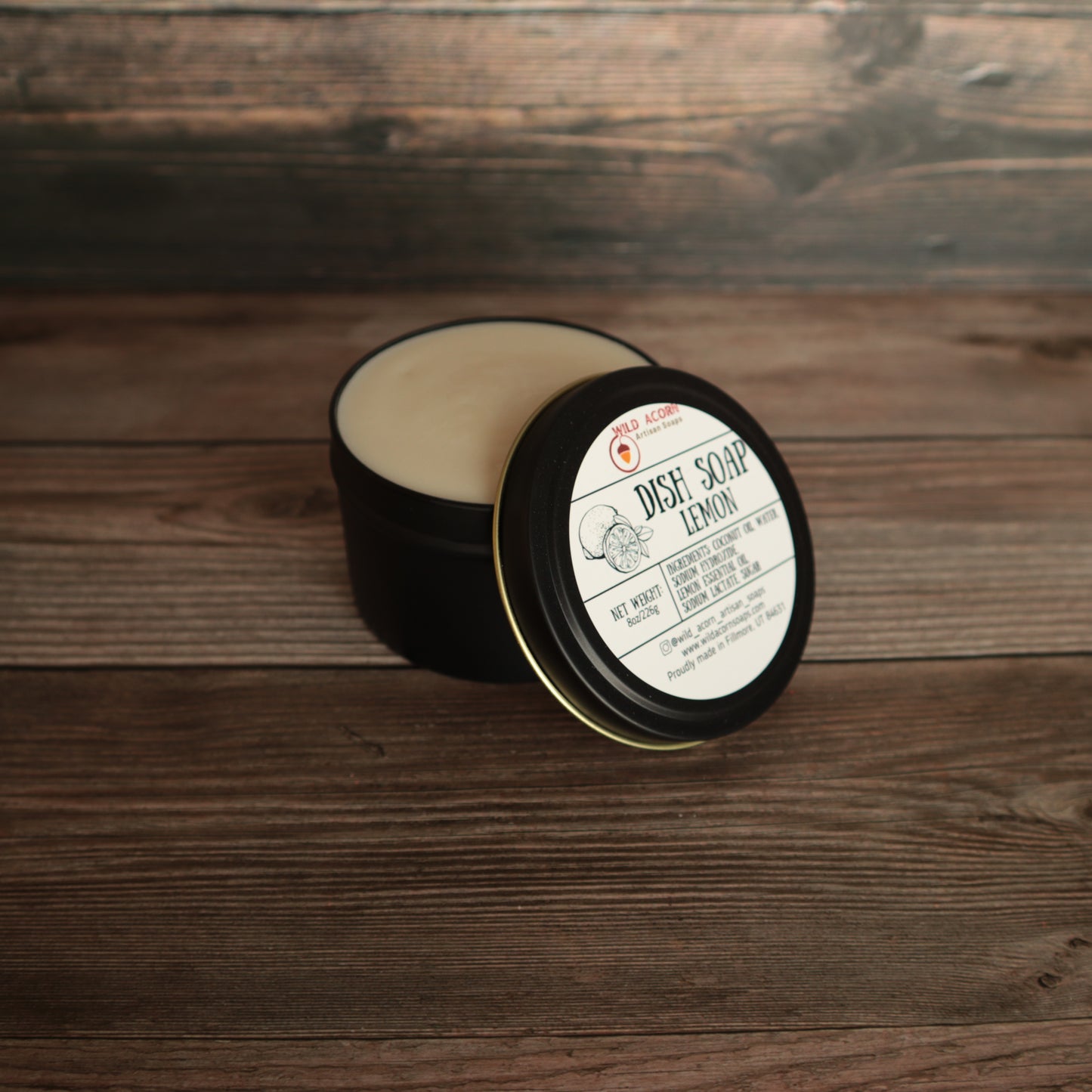 black candle like jar with lid open holding a pale yellow solid dish soap