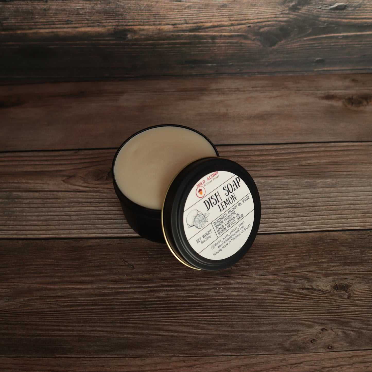 black candle like jar with lid open holding a pale yellow solid dish soap