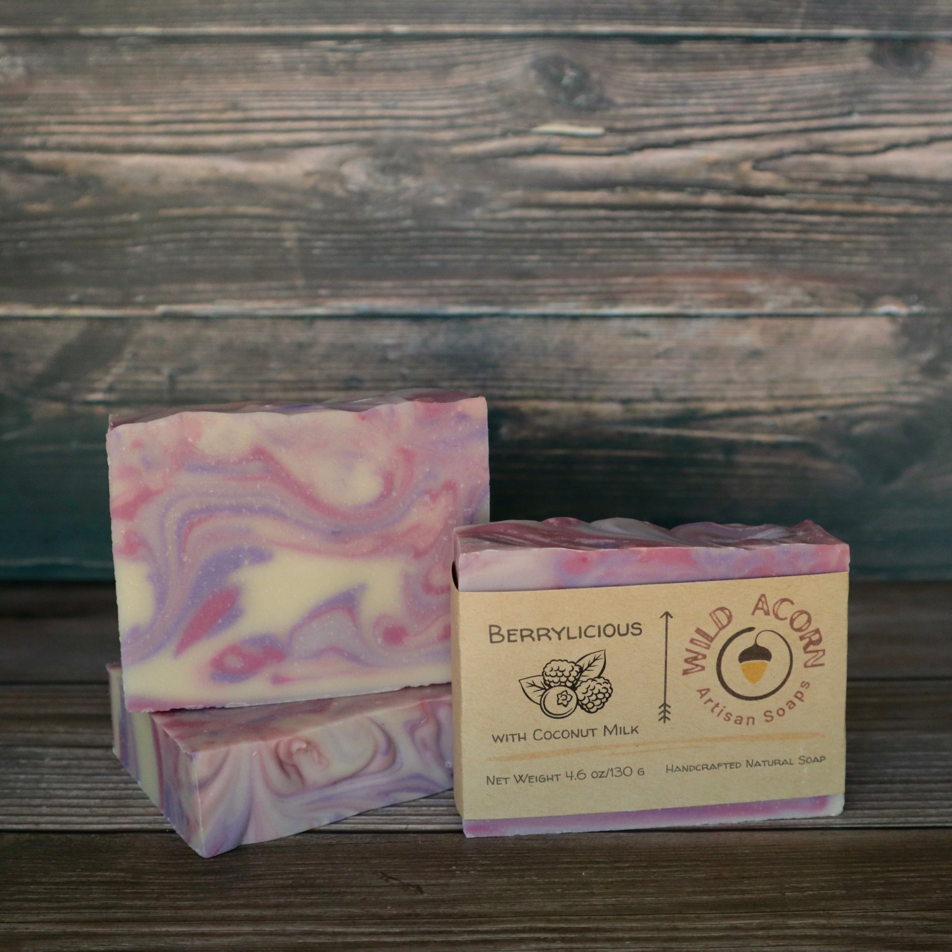Three bars of soap colored pink, purple and white swirled together to represent berry colors. One bar has a label on it with a picture of two raspberries and a blueberry and two leaves.