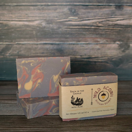 Three bars of soap with orange/red, brown, and cream colored swirls. One bar has a label on it with a picture of a man riding a horse.