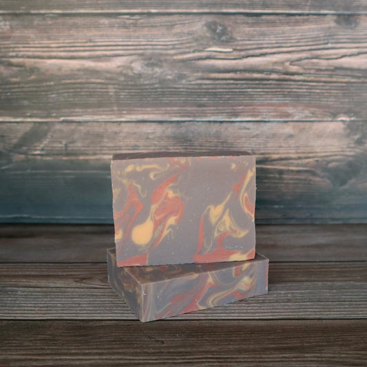 Two bars of soap with orange/red, brown, and cream colored swirls.