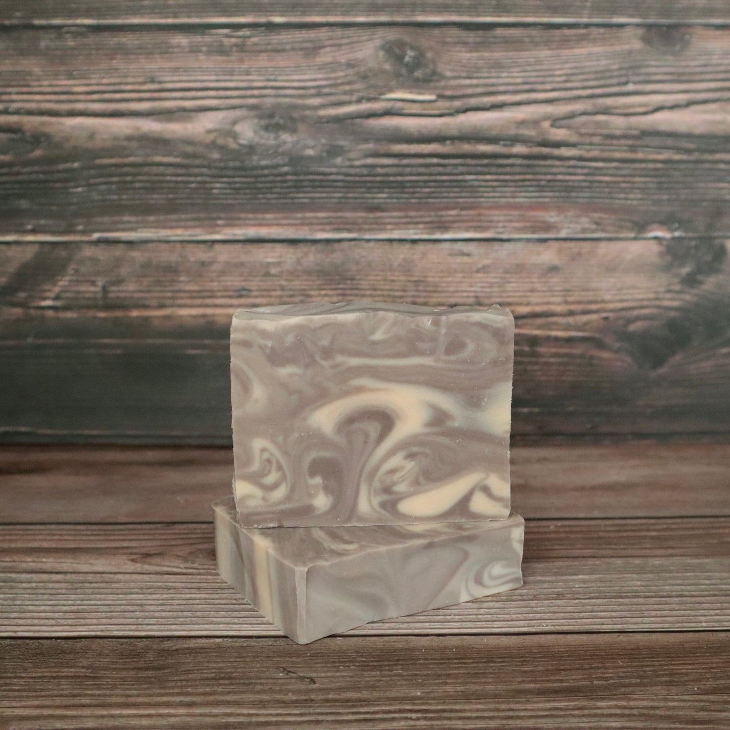 Two bars of soap with light brown and white/cream swirls resembling wood grain.