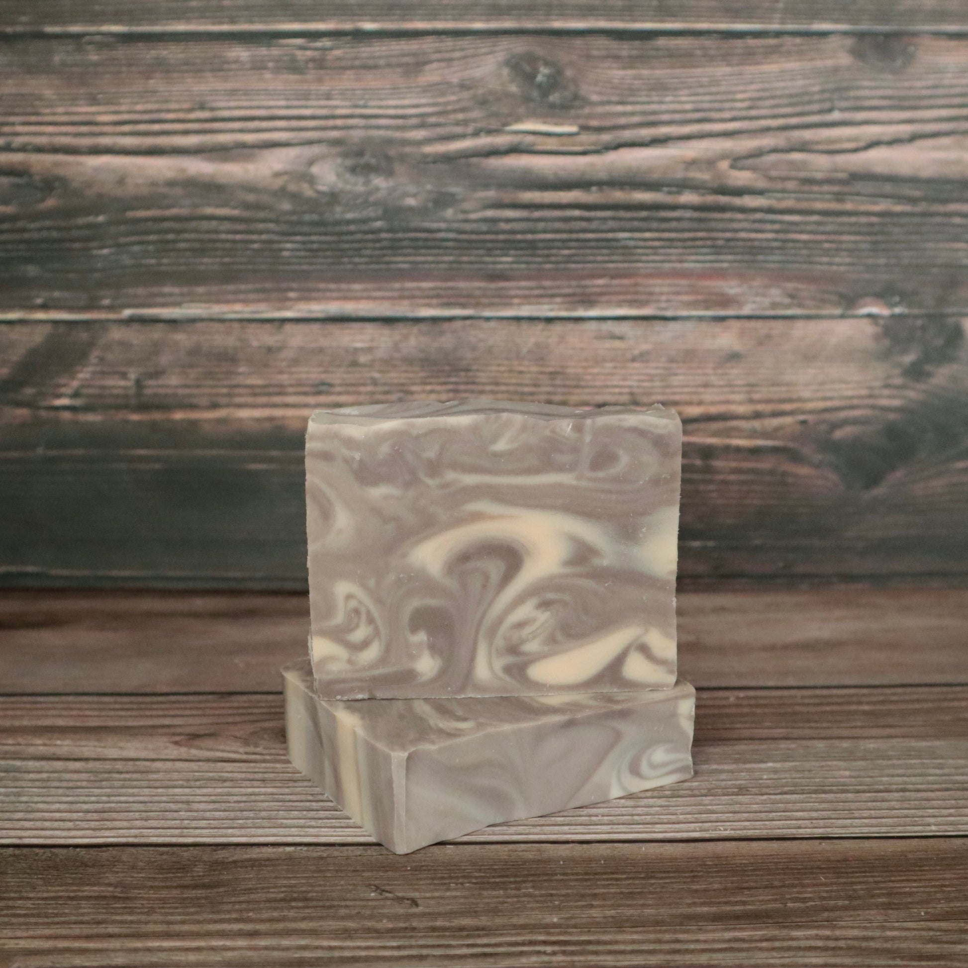 Two bars of soap with light brown and white/cream swirls resembling wood grain.