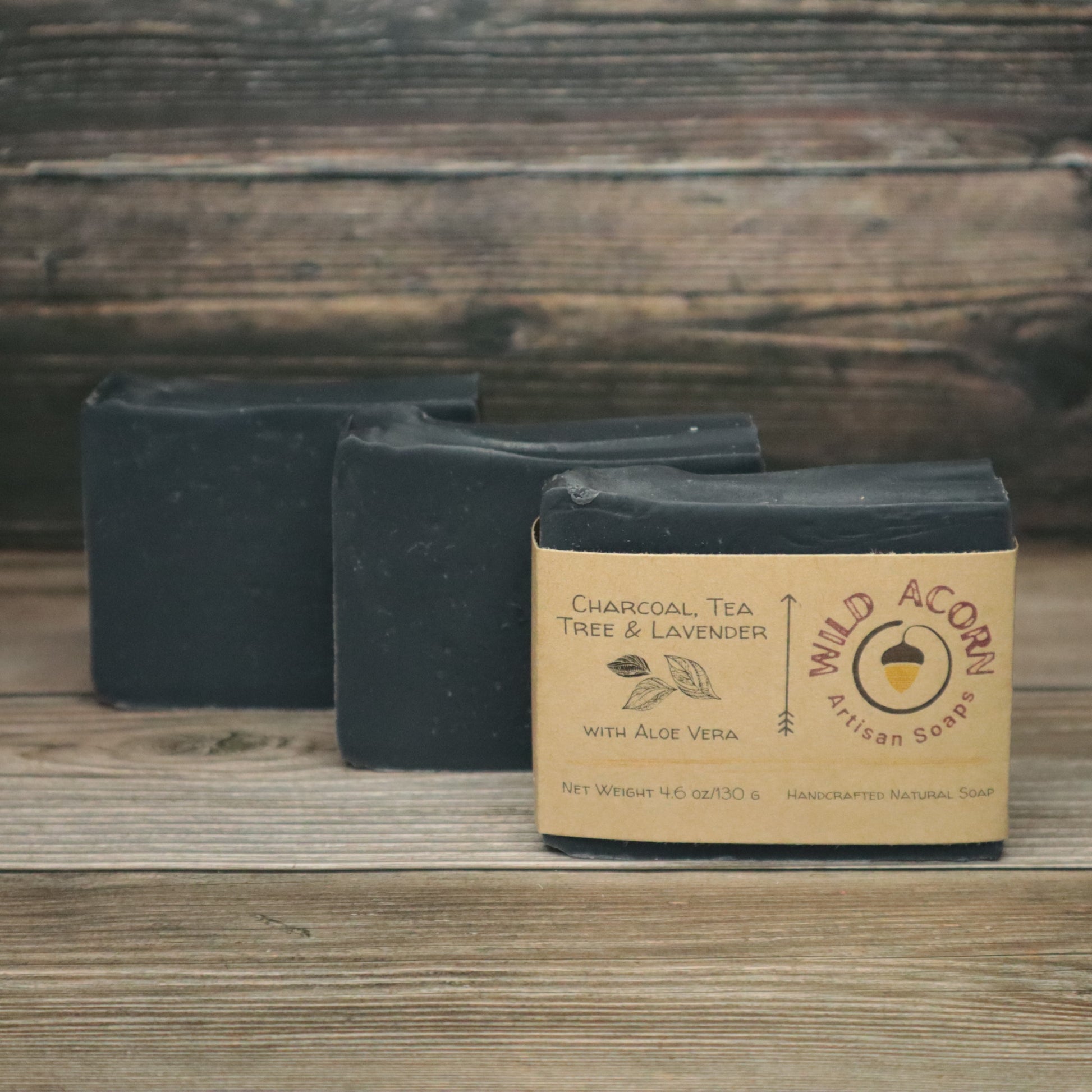 picture of  3 bars of soap, solid black. One has a tan paper label on it with a picture of leaves on it.