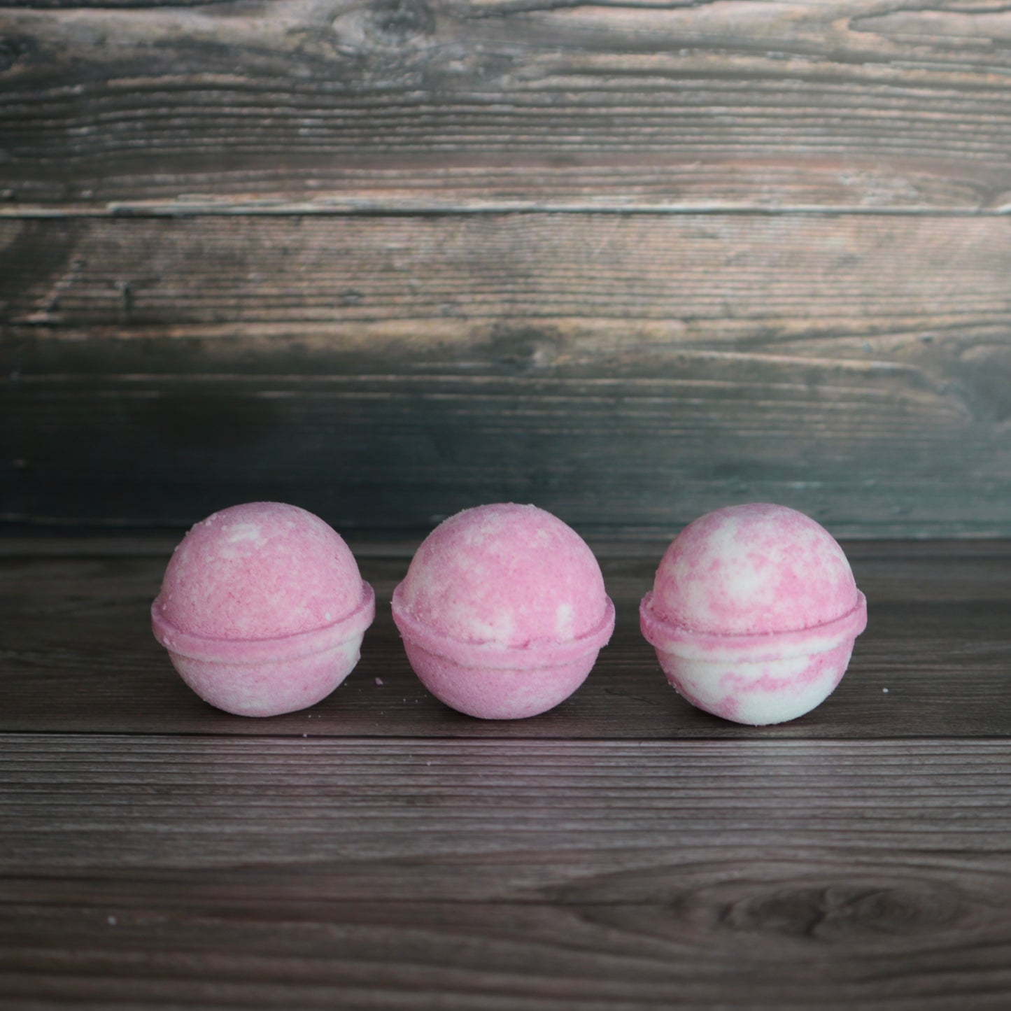 3 round pink and white marbled bath bombs, lined up.