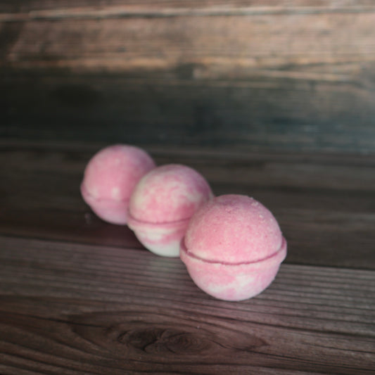 3 round pink and white marbled bath bombs, lined up.