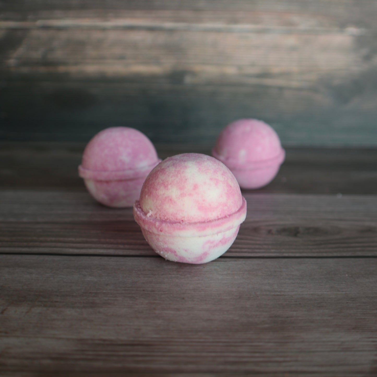 3 round pink and white marbled bath bombs.