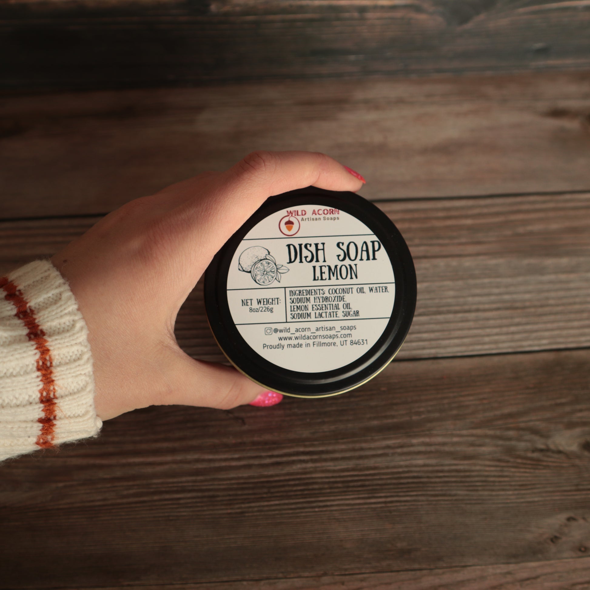 black candle like jar with solid dish soap label on top with a hand holding the jar