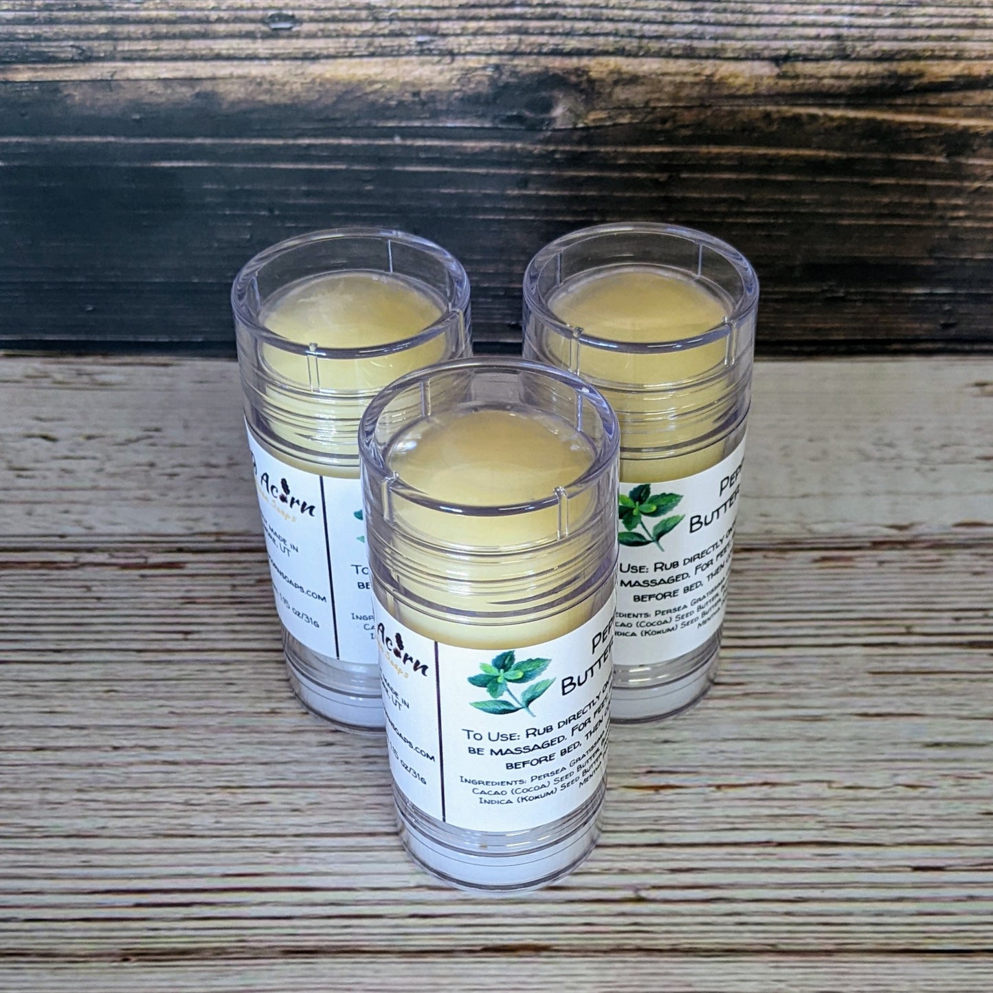 Three clear plastic tubes with a light ivory colored product inside. The labels have a picture of a peppermint plant on them. 